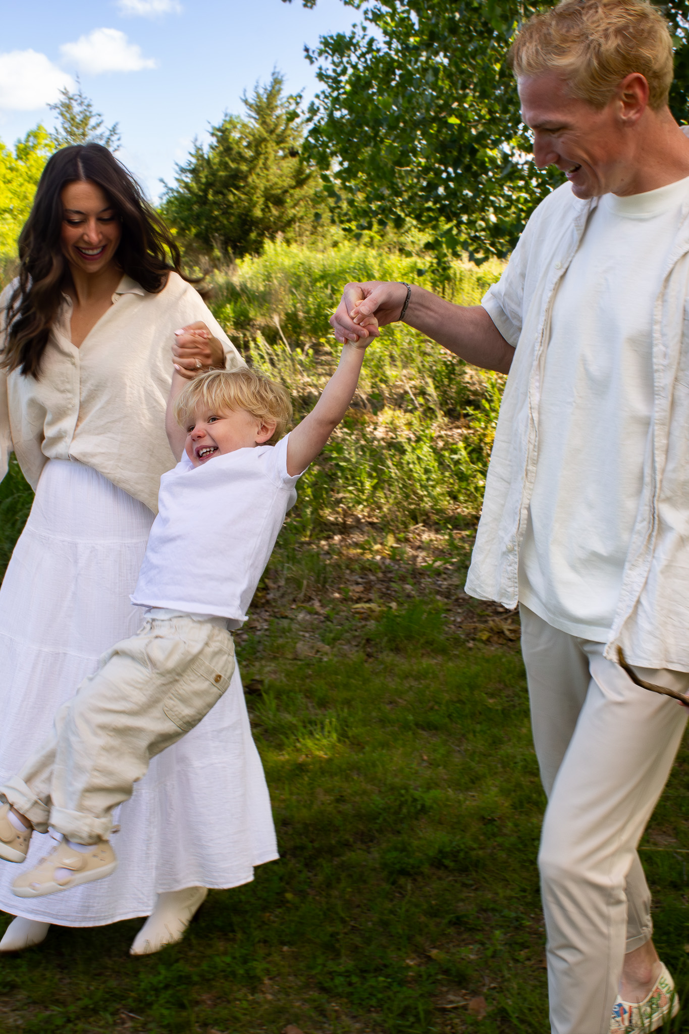Young parents swinging child in nature marsh